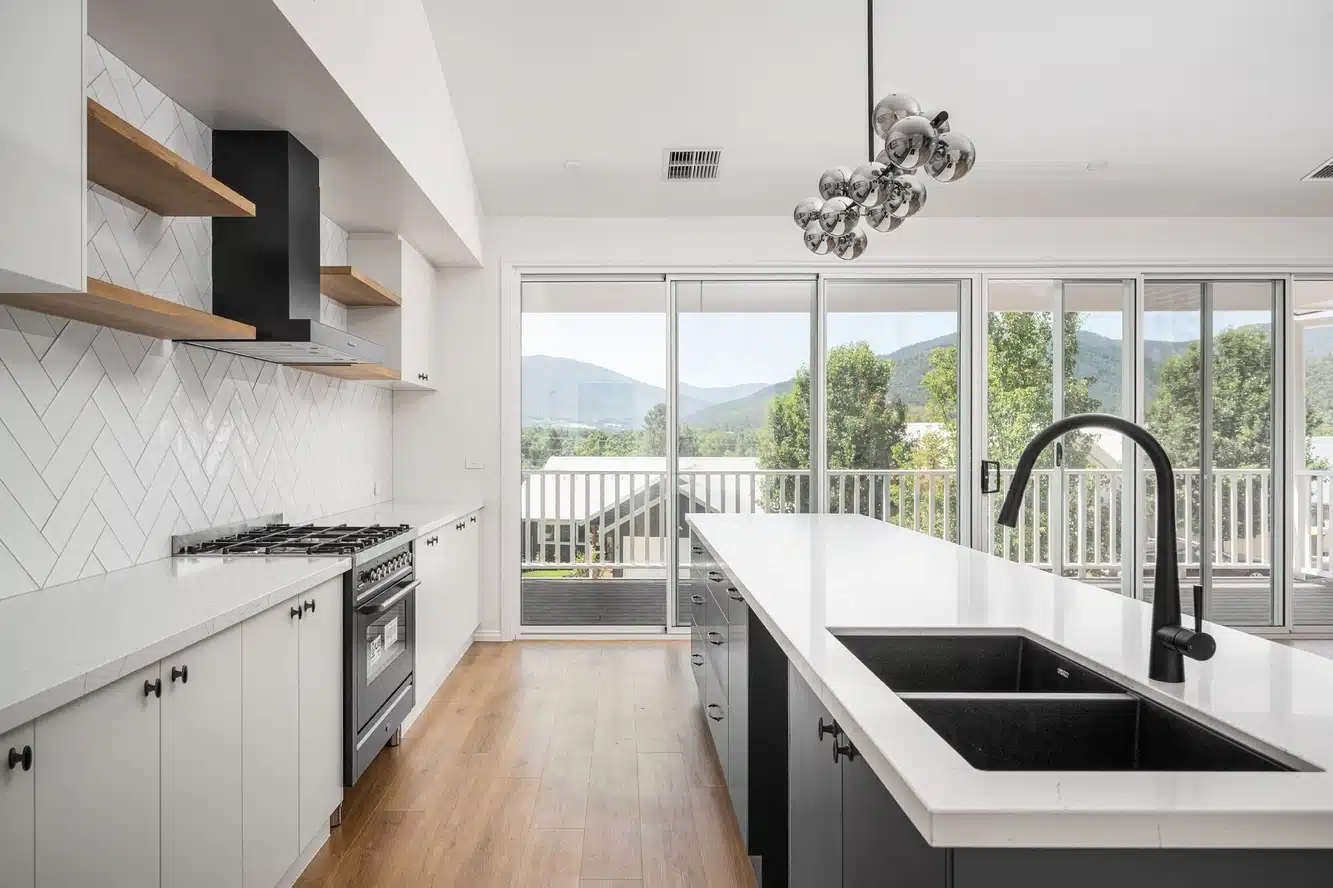 custom kitchen with timber floors, monochrome benchtop, black and white cabinetry, wit glass sliding doors.