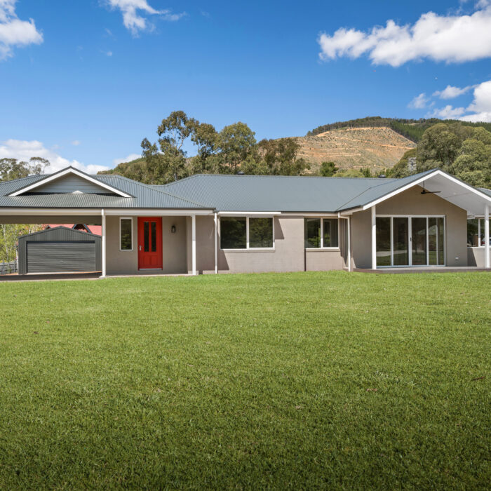 Light grey home with dark grey roof with green grass